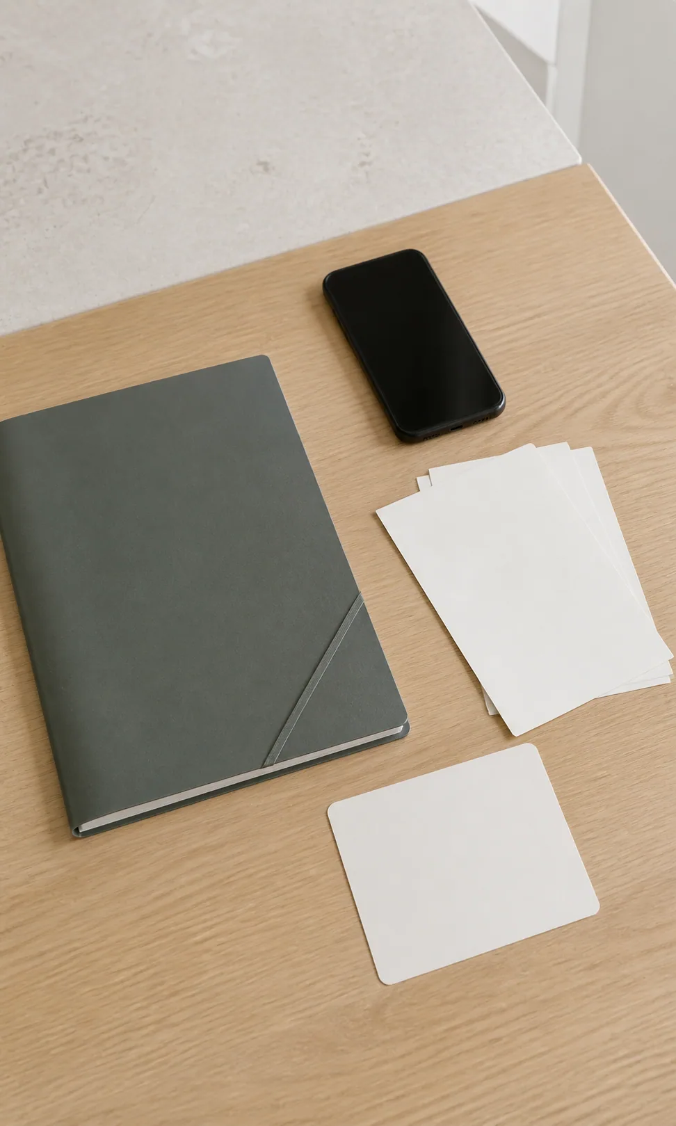 A slim folder, dark-screen phone, blank checklist card, and clean papers prepared for the first 72 hours.